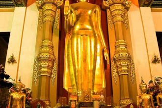 Grand bouddha debout doré dans un sanctuaire thaïlandais