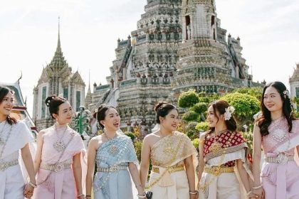 Visiteuses en costume traditionnel thaïlandais devant les prangs du Wat Arun à Bangkok