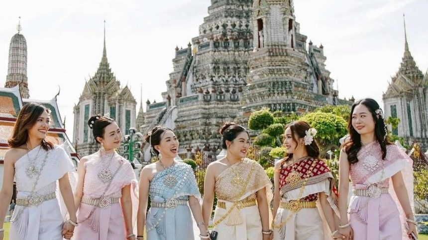 Visiteuses en costume traditionnel thaïlandais devant les prangs du Wat Arun à Bangkok