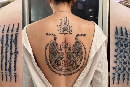 Tatouages sak yant traditionnels : lignes de yantra sur l'épaule et tigres jumeaux dans le dos