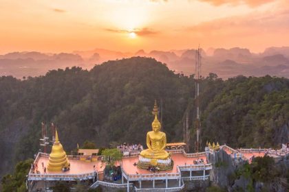 Le sommet du Wat Tham Seua et son grand Bouddha doré dominant la vallée de Krabi au coucher du soleil