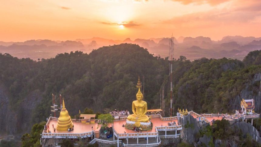 Le sommet du Wat Tham Seua et son grand Bouddha doré dominant la vallée de Krabi au coucher du soleil